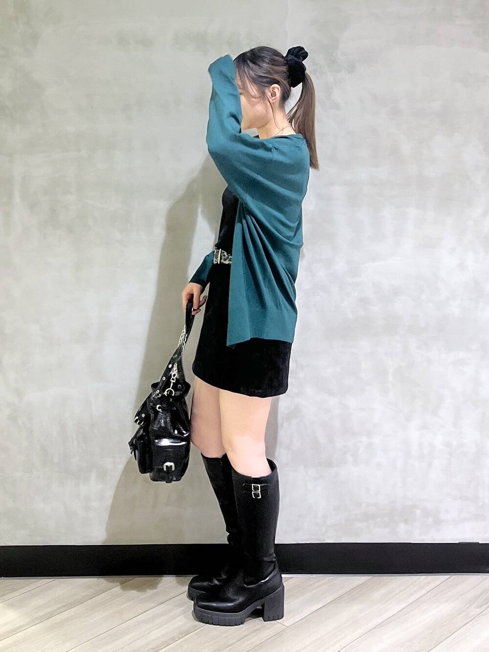 ブラック系のブーツ、ブラック系のスカート、グリーン系のカーディガン/ボレロを着用したレディースの秋コーディネートの3枚目の写真