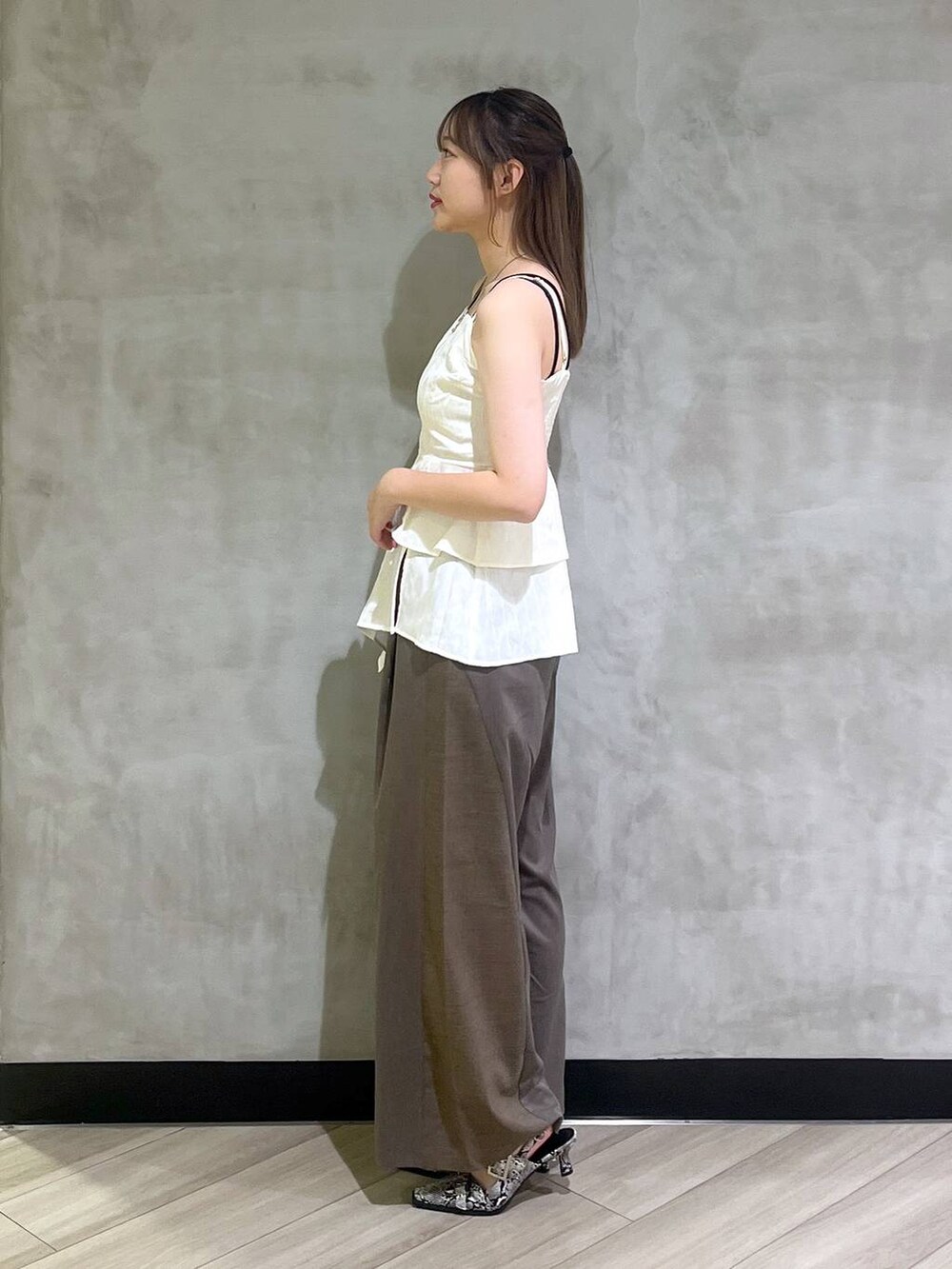 ホワイト系のパンプス、ブラウン系のスラックス、ホワイト系のキャミソールを着用したレディースの夏コーディネートの3枚目の写真