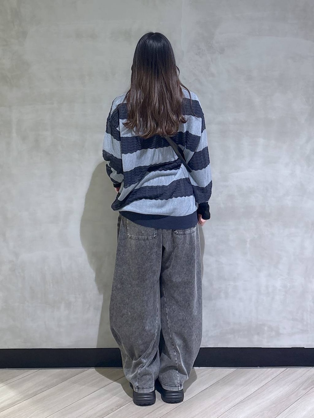 ブラック系のスニーカー、ブラック系のデニムパンツ、ブルー系のポロシャツを着用したレディースの春コーディネートの5枚目の写真