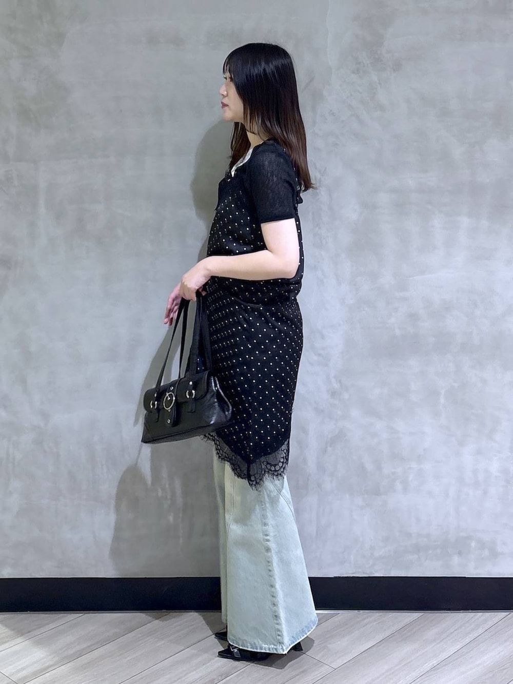 ブラック系のチュニック、ブルー系のデニムパンツ、ブラック系のサンダルを着用したレディースの夏コーディネートの4枚目の写真