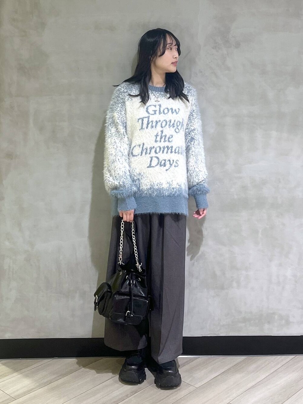 ブラック系のスニーカー、ブルー系のニット/セーター、グレー系のスラックスを着用したレディースの秋コーディネートの2枚目の写真