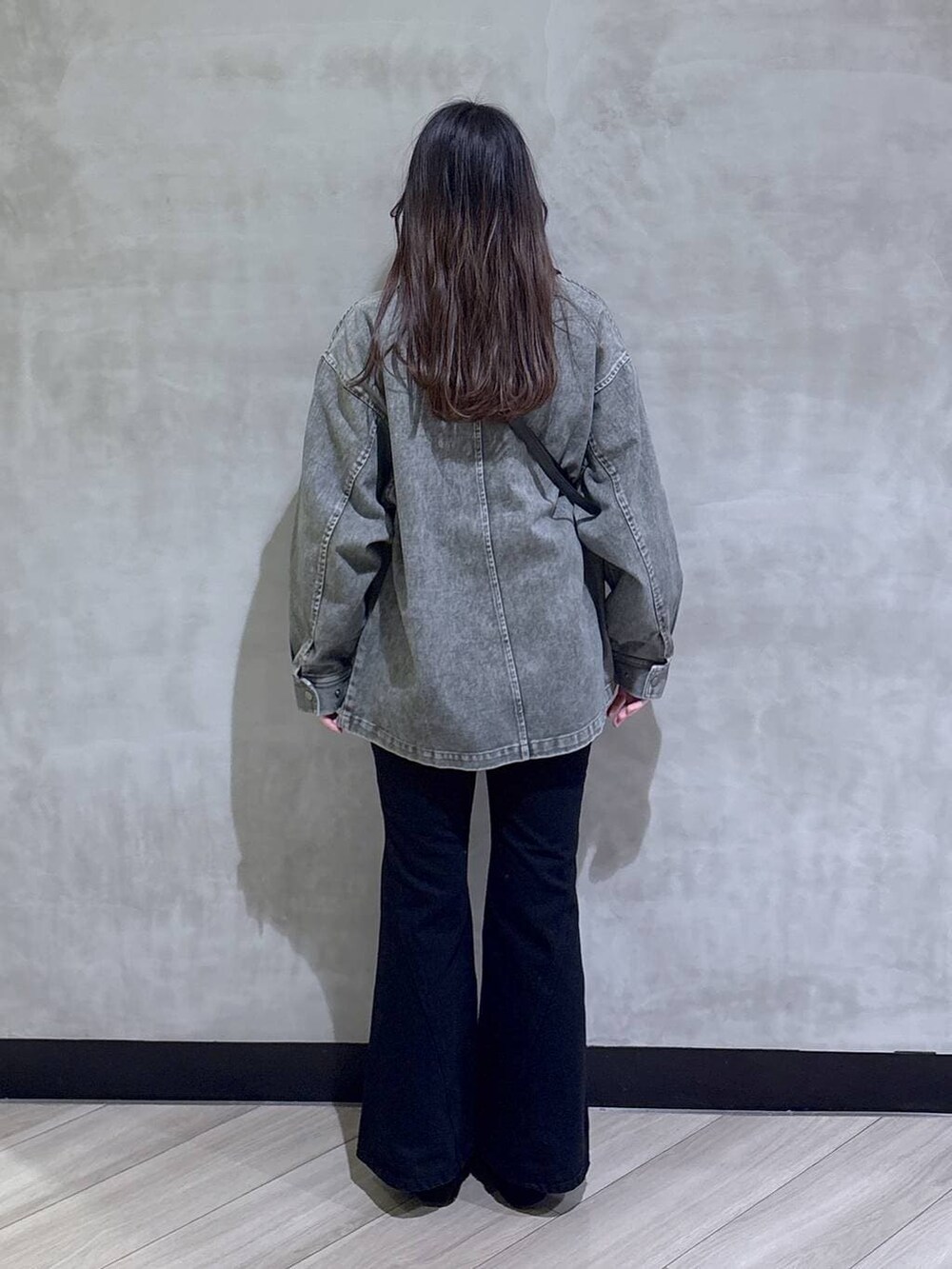 ブラック系のデニムパンツ、ブラック系のモカシン/デッキシューズ、グリーン系のニット/セーターを着用したレディースの春コーディネートの5枚目の写真