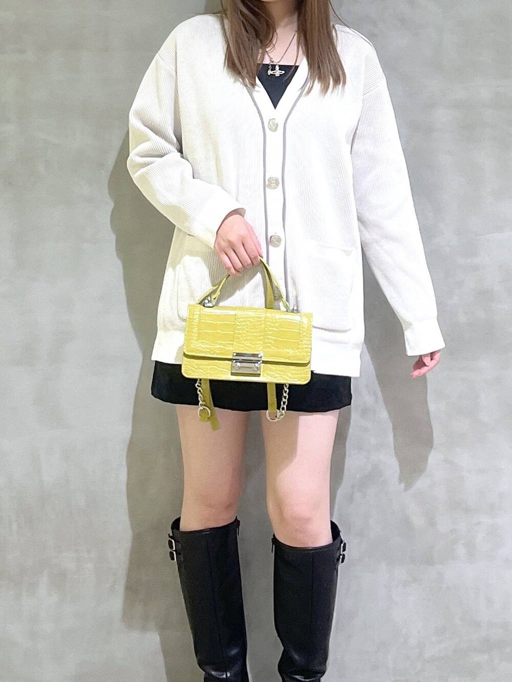 ブラック系のブーツ、ブラック系のスカート、ホワイト系のカーディガン/ボレロを着用したレディースの秋コーディネートの2枚目の写真