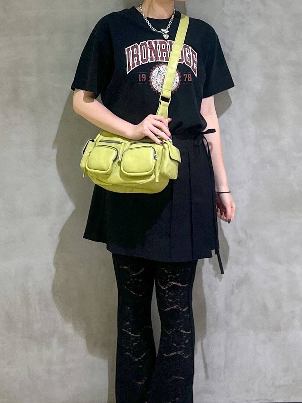 ブラック系のサンダル、ブラック系のスカート、グリーン系のショルダーバッグを着用したレディースの春コーディネートの2枚目の写真