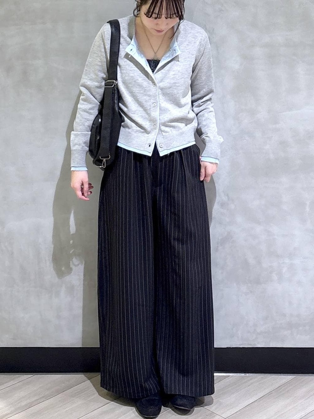 ブラック系のスラックス、グレー系のカーディガン/ボレロ、ブラック系のモカシン/デッキシューズを着用したレディースの春コーディネートの2枚目の写真