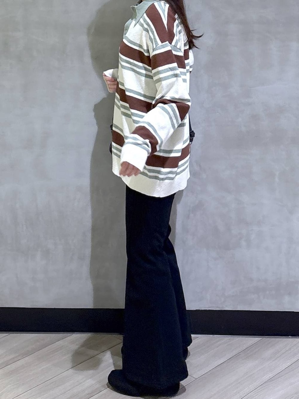 ブラック系のデニムパンツ、ブラック系のモカシン/デッキシューズ、グリーン系のニット/セーターを着用したレディースの春コーディネートの4枚目の写真