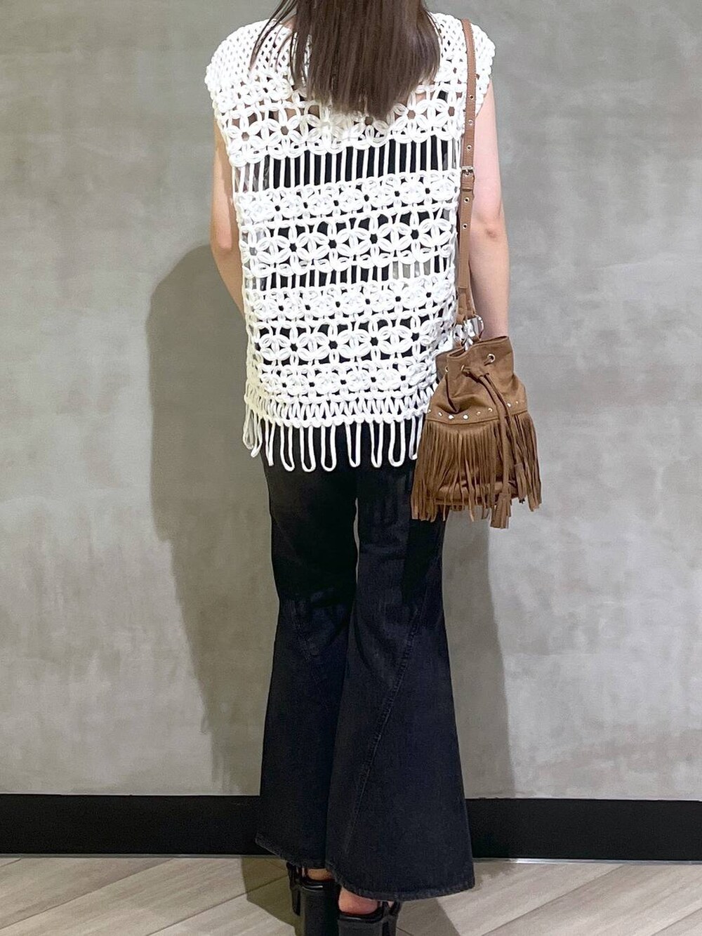 ブラック系のブーツ、ブラック系のデニムパンツ、ホワイト系のベストを着用したレディースの夏コーディネートの6枚目の写真