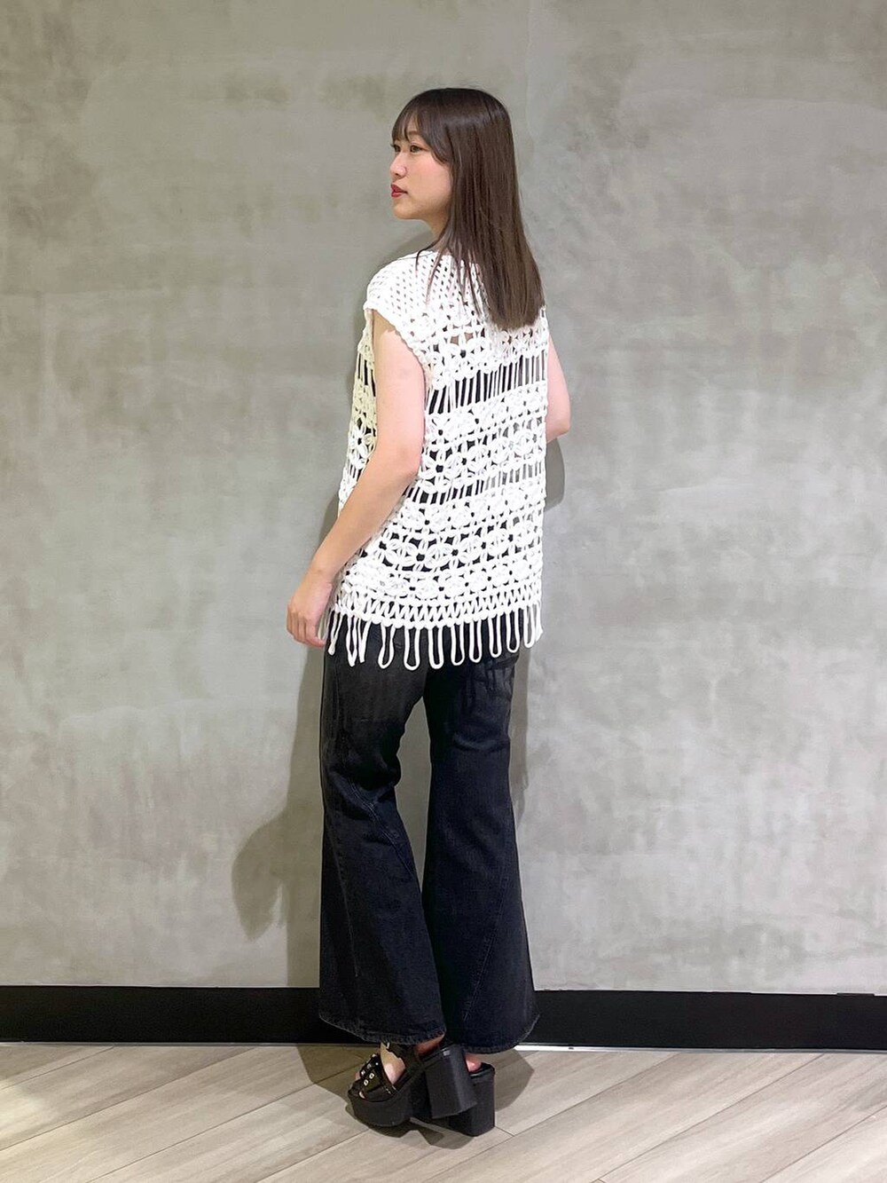 ブラック系のブーツ、ブラック系のデニムパンツ、ホワイト系のベストを着用したレディースの夏コーディネートの9枚目の写真