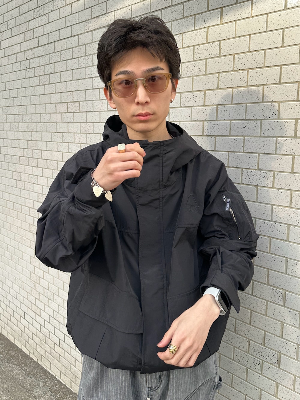 ブラック系のマウンテンパーカー、ブラック系のデニムパンツ、グリーン系のサングラスを着用したメンズの冬コーディネートの2枚目の写真