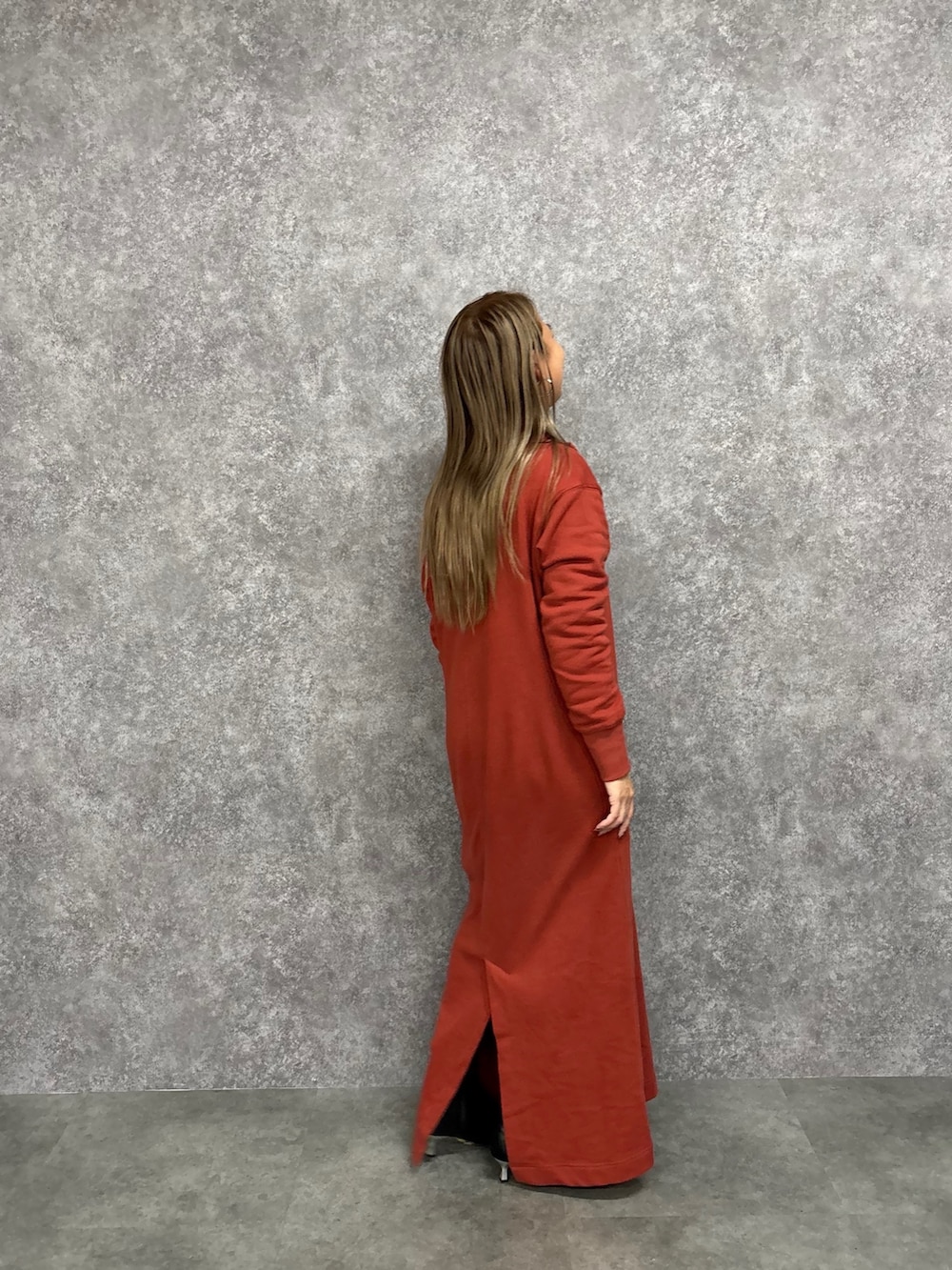 オレンジ系のワンピース、ブラック系のブーツを着用したレディースの冬コーディネートの3枚目の写真