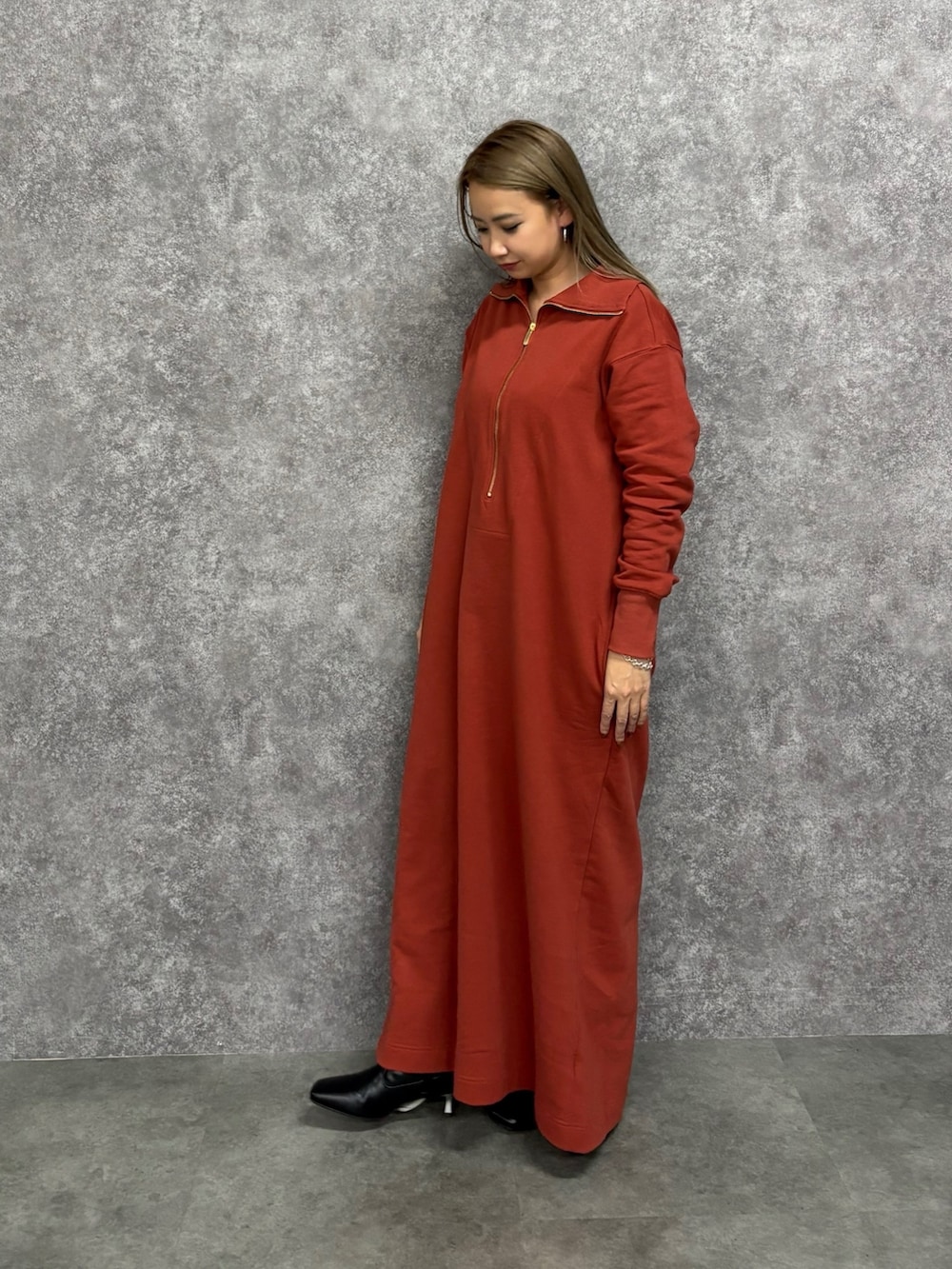 オレンジ系のワンピース、ブラック系のブーツを着用したレディースの冬コーディネートの2枚目の写真