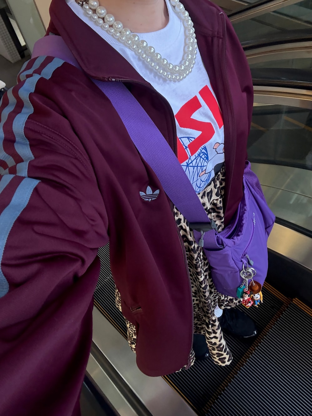 ブラック系のスニーカー、パープル系のショルダーバッグ、パープル系のジャケット/アウターを着用したレディースの春コーディネートの4枚目の写真