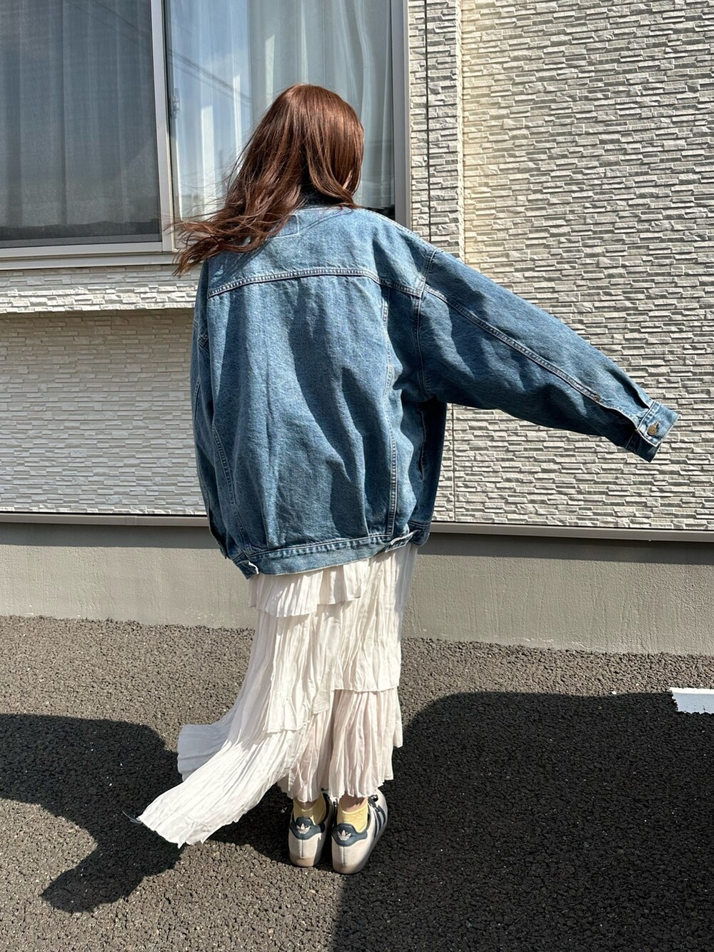 ブルー系のデニムジャケット、グレー系のスウェット、ホワイト系のスカートを着用したレディースの春コーディネートの4枚目の写真