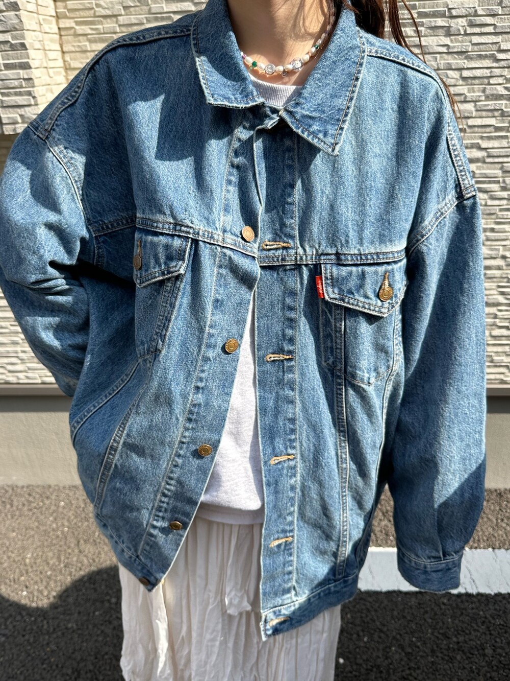 ブルー系のデニムジャケット、グレー系のスウェット、ホワイト系のスカートを着用したレディースの春コーディネートの7枚目の写真