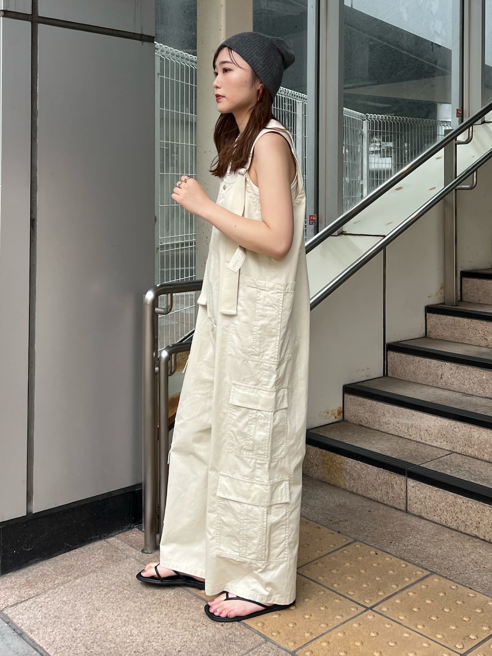 ベージュ系のサロペット/オーバーオール、ホワイト系のタンクトップ、グレー系のニットキャップ/ビーニーを着用したレディースの夏コーディネートの2枚目の写真