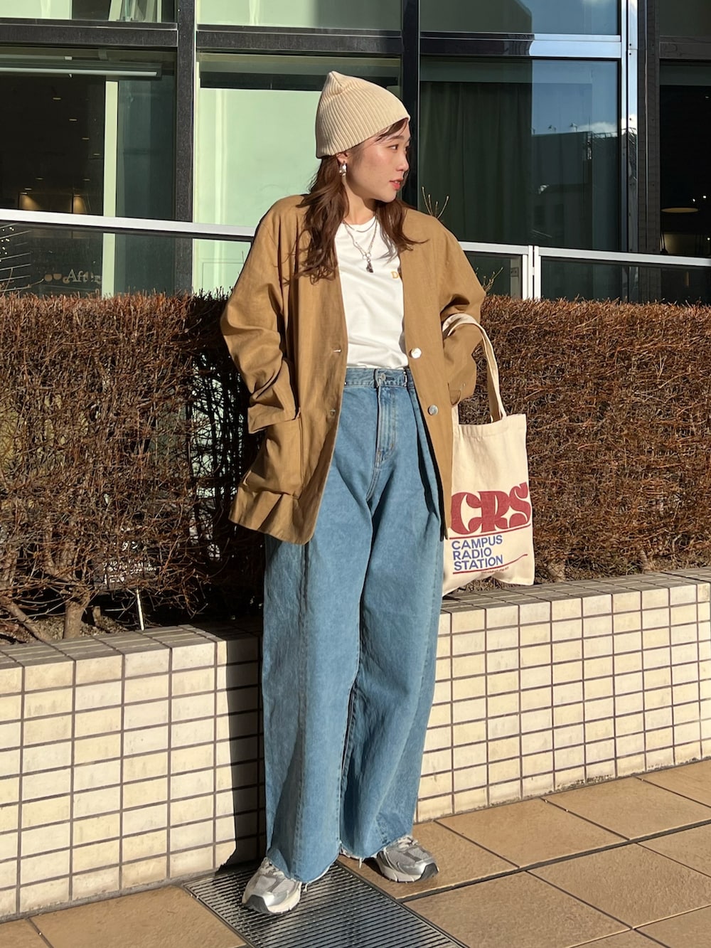 ブルー系のデニムパンツ、レッド系のトートバッグ、ベージュ系のテーラードジャケットを着用したレディースの春コーディネートの2枚目の写真