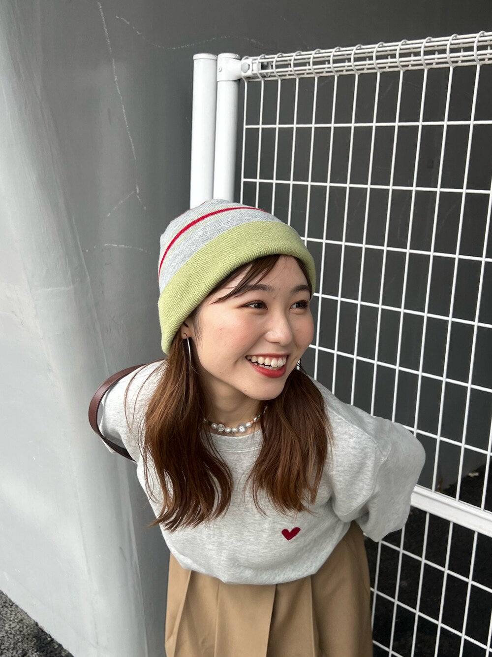 イエロー系のスカート、グレー系のスウェット、ブラウン系のハンドバッグを着用したレディースの夏コーディネートの7枚目の写真