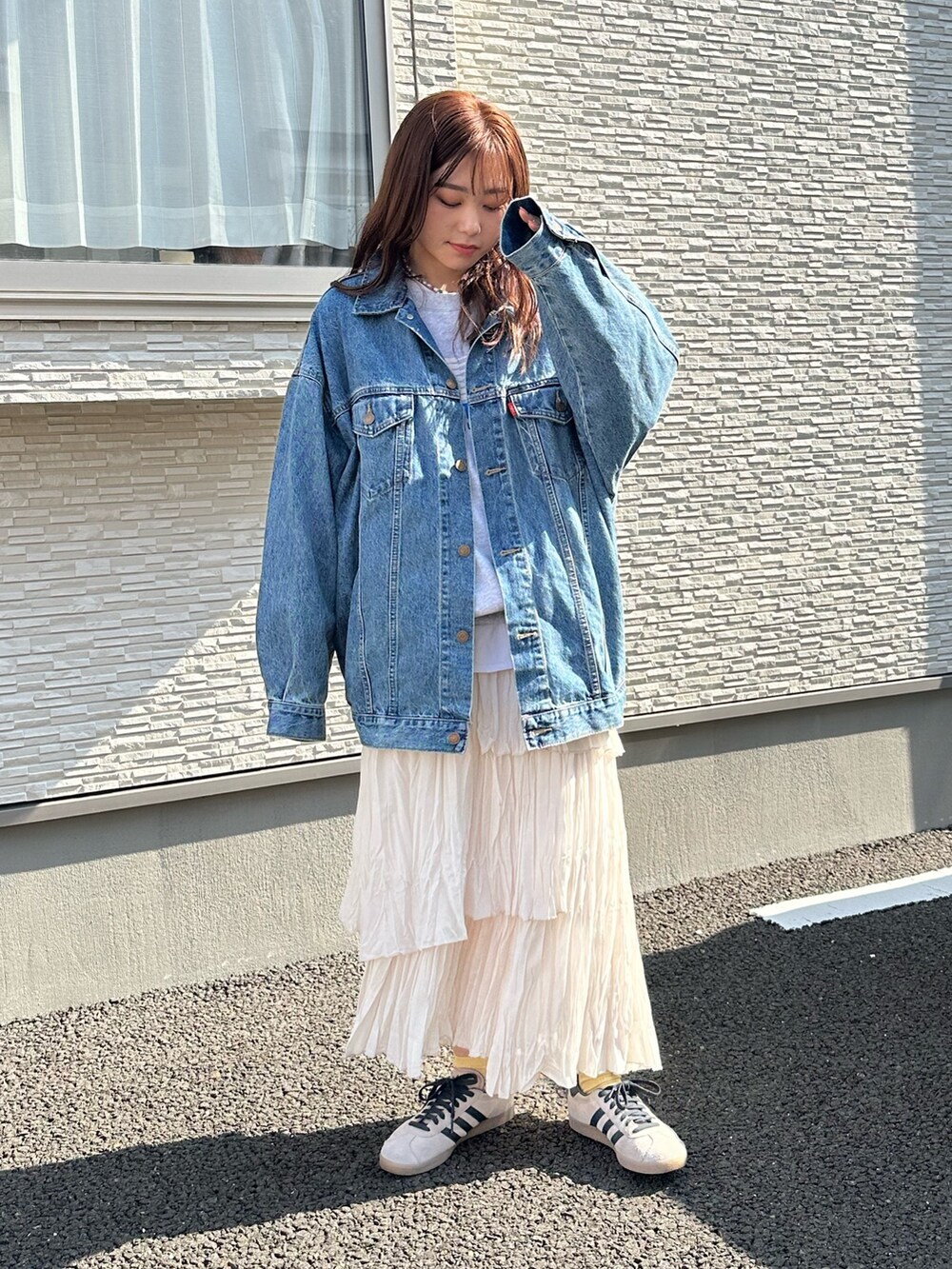 ブルー系のデニムジャケット、グレー系のスウェット、ホワイト系のスカートを着用したレディースの春コーディネートの2枚目の写真