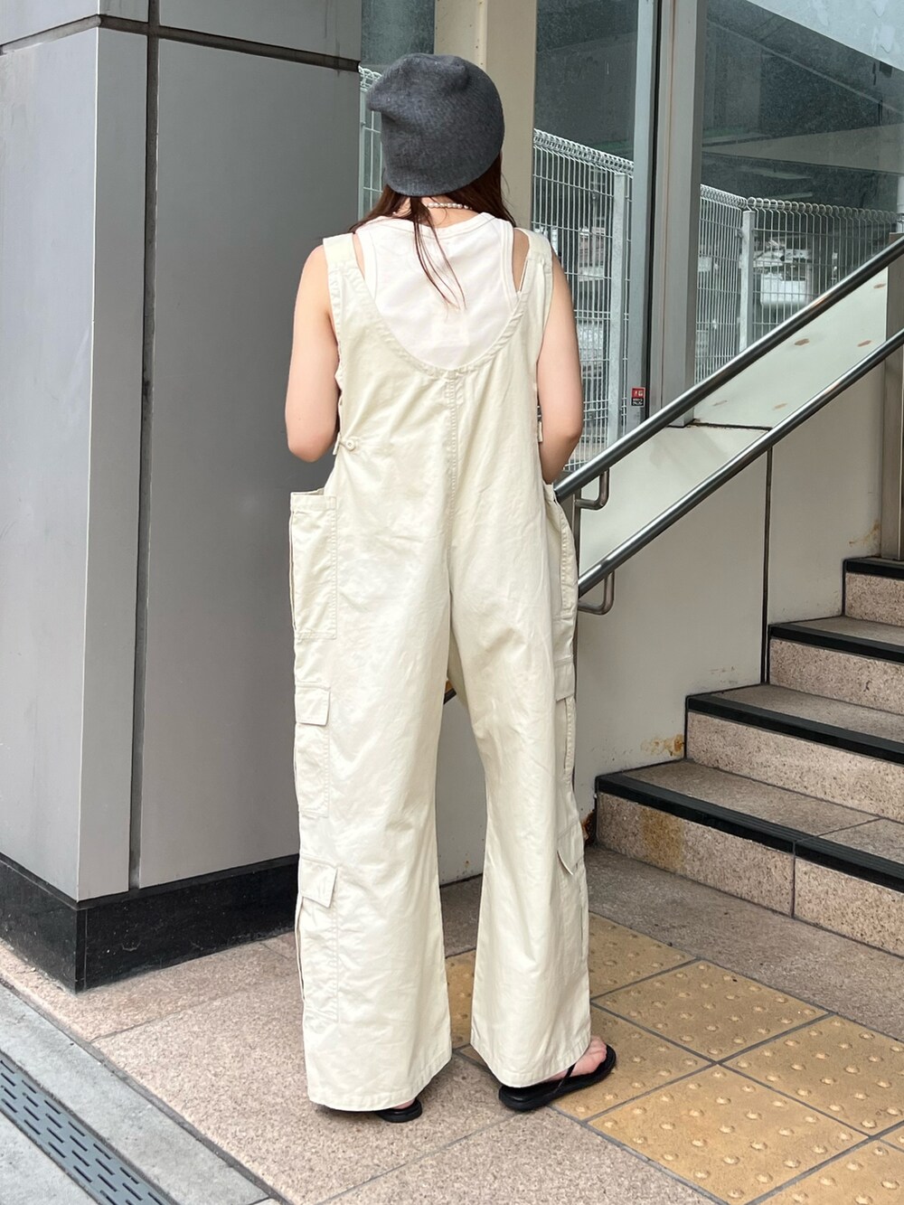 ベージュ系のサロペット/オーバーオール、ホワイト系のタンクトップ、グレー系のニットキャップ/ビーニーを着用したレディースの夏コーディネートの3枚目の写真