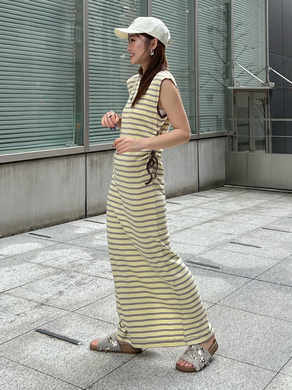 ブルー系のキャミソール、イエロー系のワンピース、ホワイト系のサンダルを着用したレディースの春コーディネートの6枚目の写真