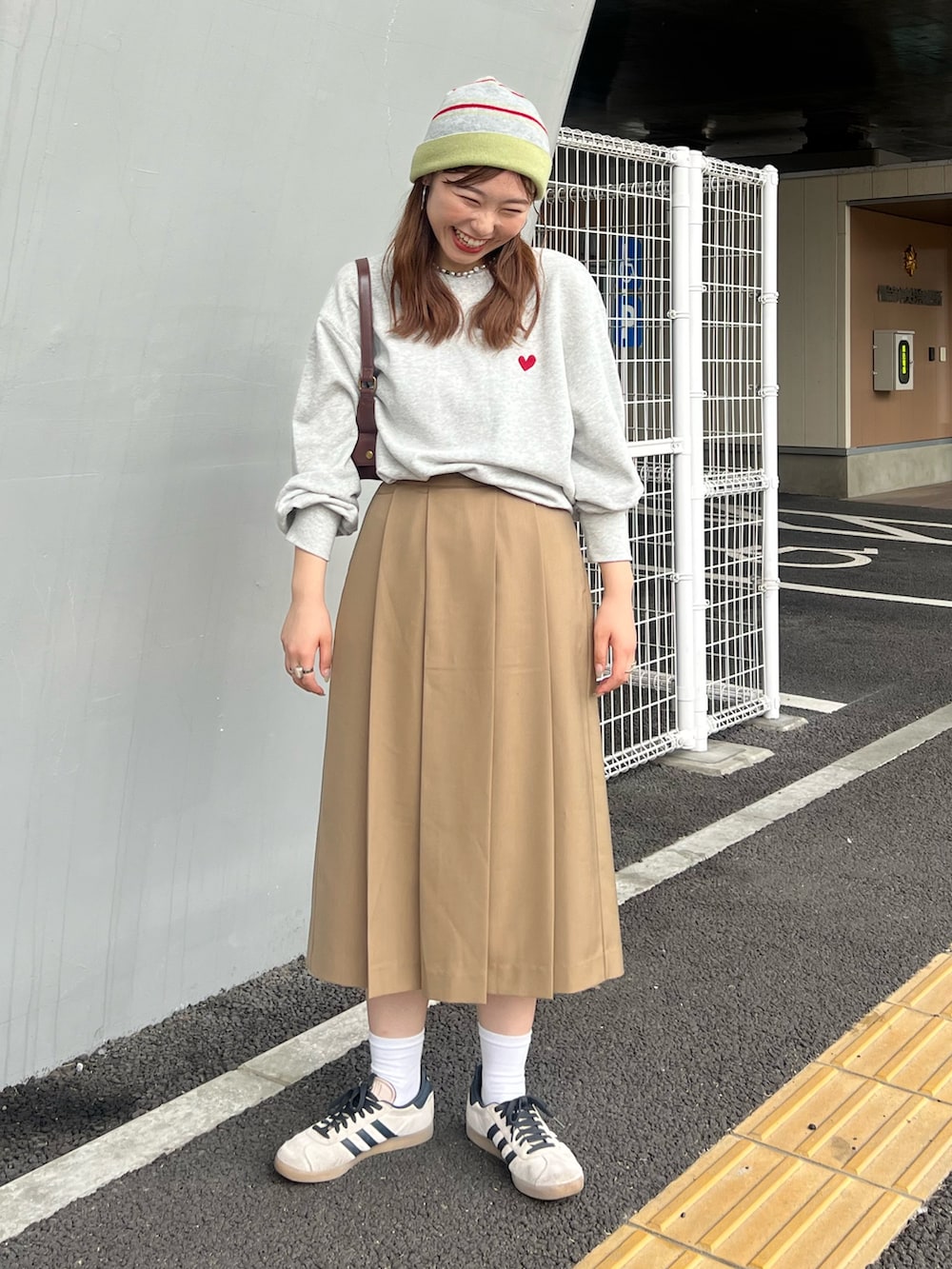 イエロー系のスカート、グレー系のスウェット、ブラウン系のハンドバッグを着用したレディースの夏コーディネートの2枚目の写真