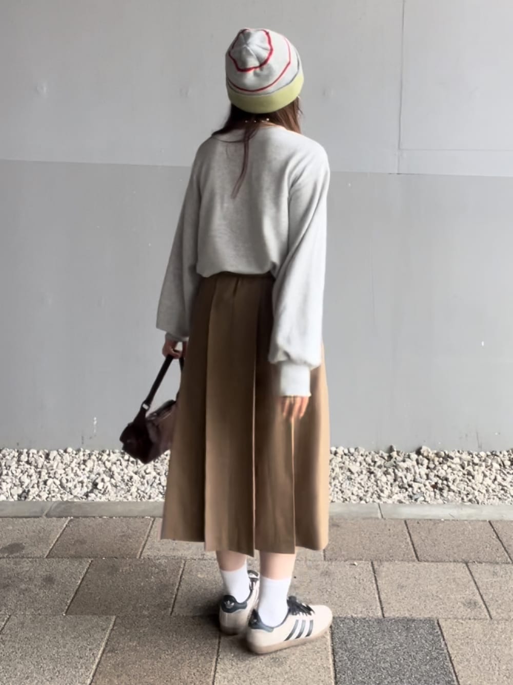 イエロー系のスカート、グレー系のスウェット、ブラウン系のハンドバッグを着用したレディースの夏コーディネートの4枚目の写真