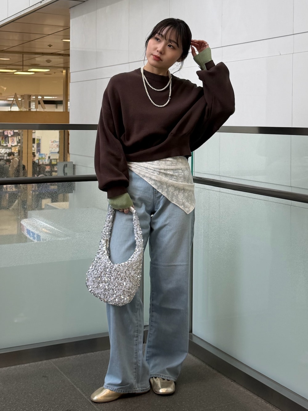 ブルー系のデニムパンツ、ブラウン系のニット/セーター、ホワイト系のハンドバッグを着用したレディースの冬コーディネートの4枚目の写真