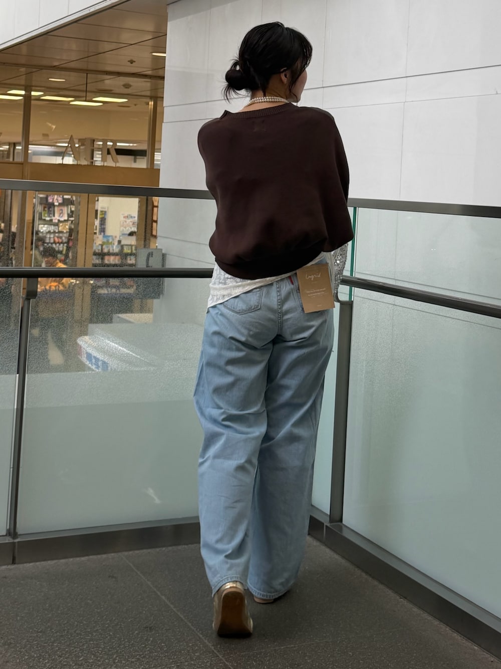 ブルー系のデニムパンツ、ブラウン系のニット/セーター、ホワイト系のハンドバッグを着用したレディースの冬コーディネートの3枚目の写真