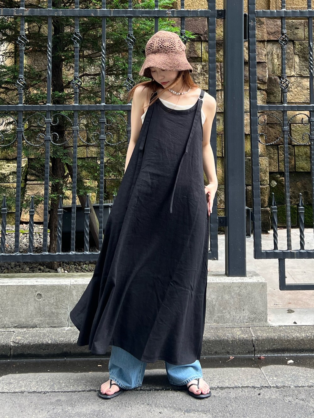 ブラック系のワンピース、ブルー系のデニムパンツ、ホワイト系のキャミソールを着用したレディースの夏コーディネートの3枚目の写真