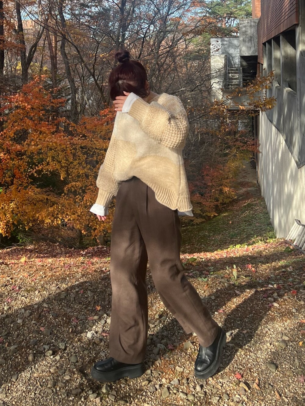 ホワイト系のニット/セーター、ブラウン系のその他パンツ、ブラック系のブーツを着用したレディースの冬コーディネートの2枚目の写真