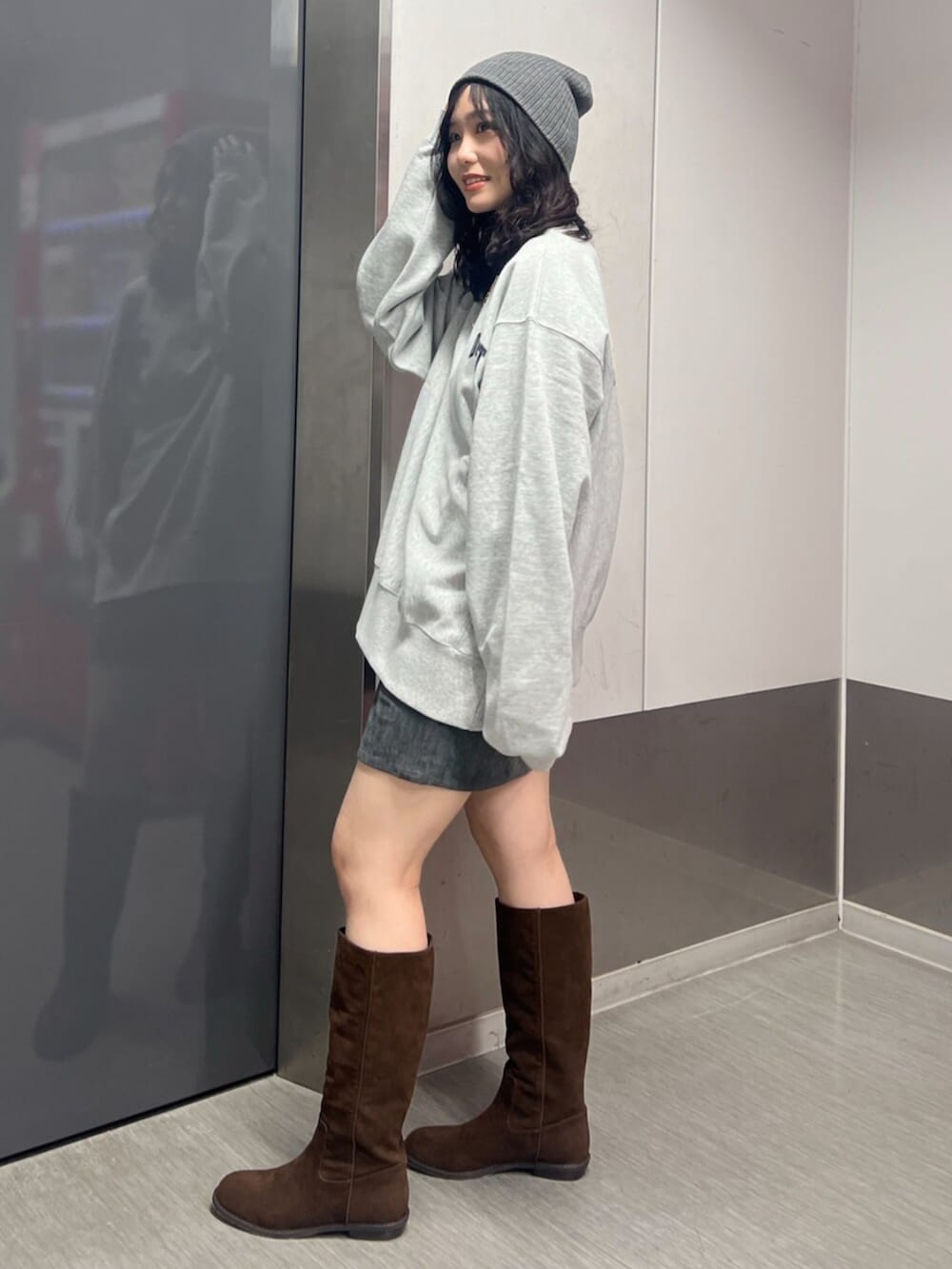 グレー系のスウェット、グレー系のスカート、ブラウン系のブーツを着用したレディースの秋コーディネートの2枚目の写真