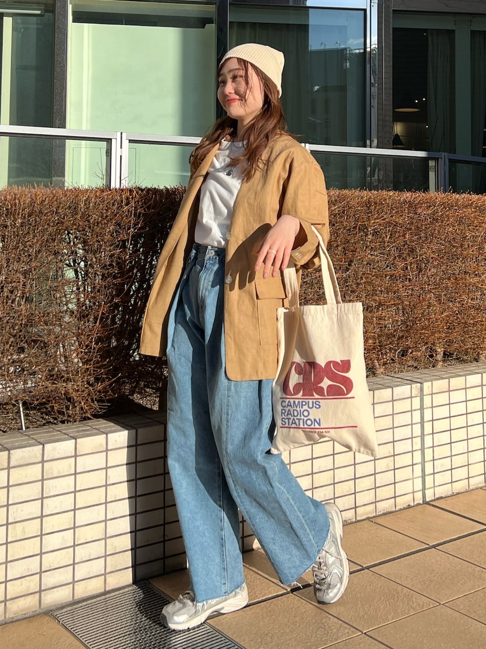 ブルー系のデニムパンツ、レッド系のトートバッグ、ベージュ系のテーラードジャケットを着用したレディースの春コーディネートの3枚目の写真