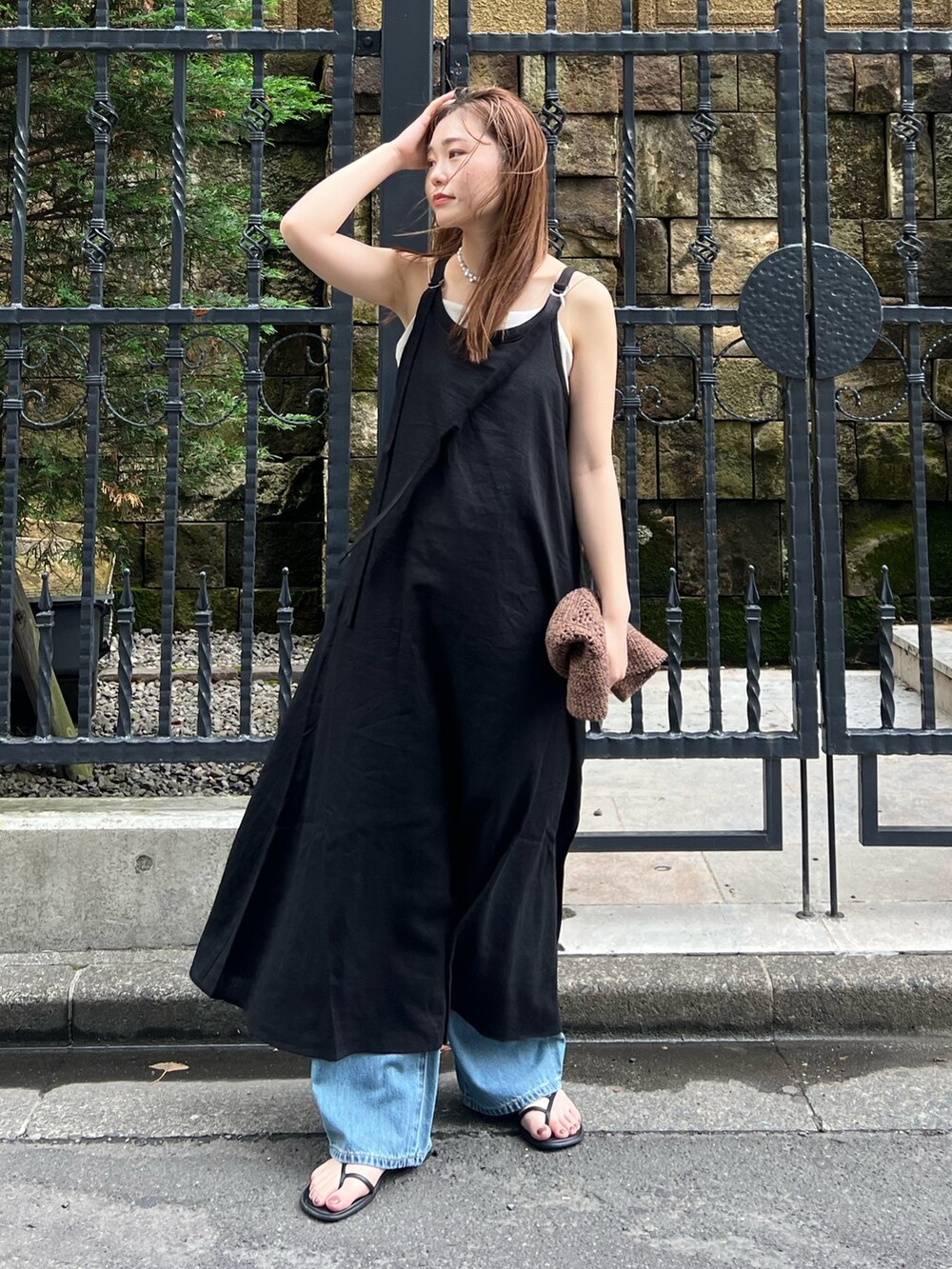 ブラック系のワンピース、ブルー系のデニムパンツ、ホワイト系のキャミソールを着用したレディースの夏コーディネートの2枚目の写真