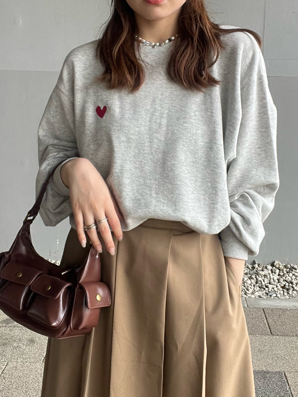 イエロー系のスカート、グレー系のスウェット、ブラウン系のハンドバッグを着用したレディースの夏コーディネートの6枚目の写真