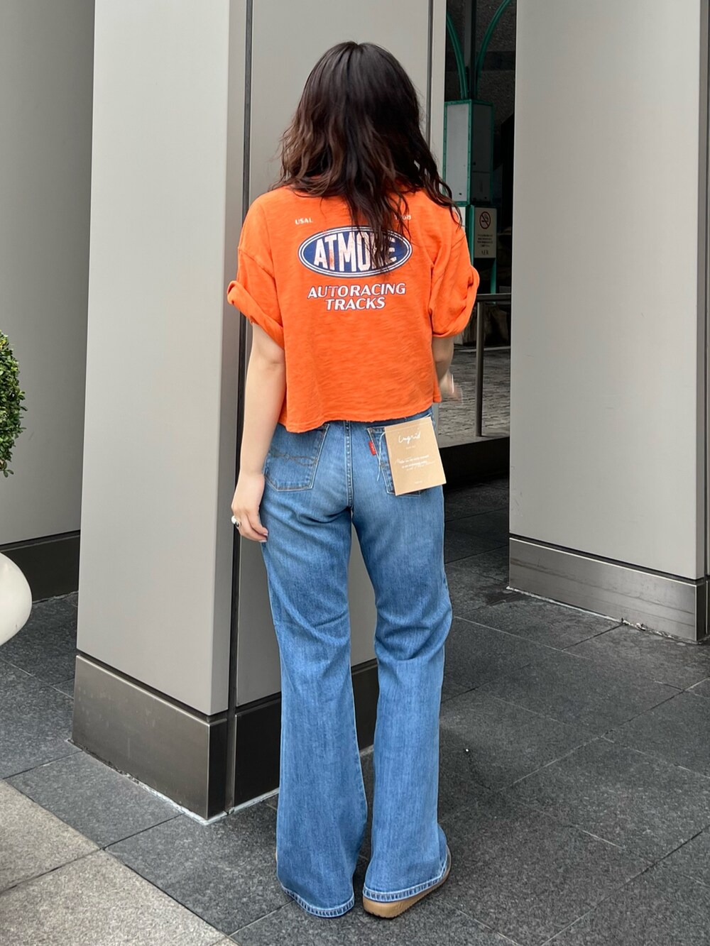 ブルー系のデニムパンツ、オレンジ系のTシャツ/カットソーを着用したレディースの春コーディネートの3枚目の写真