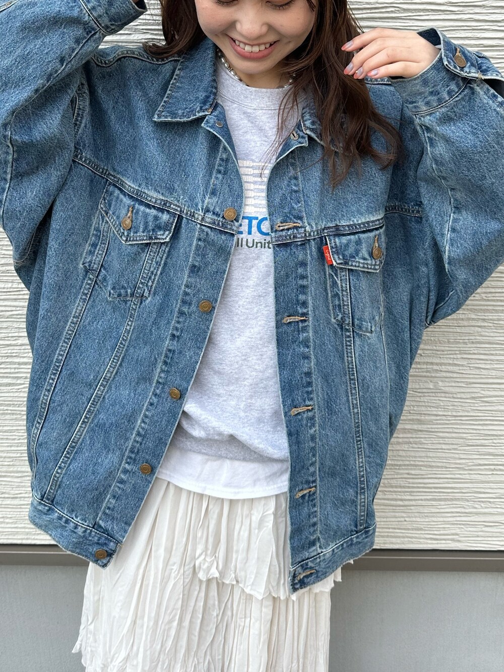 ブルー系のデニムジャケット、グレー系のスウェット、ホワイト系のスカートを着用したレディースの春コーディネートの5枚目の写真