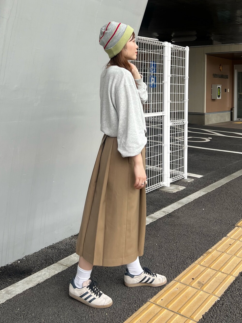 イエロー系のスカート、グレー系のスウェット、ブラウン系のハンドバッグを着用したレディースの夏コーディネートの3枚目の写真