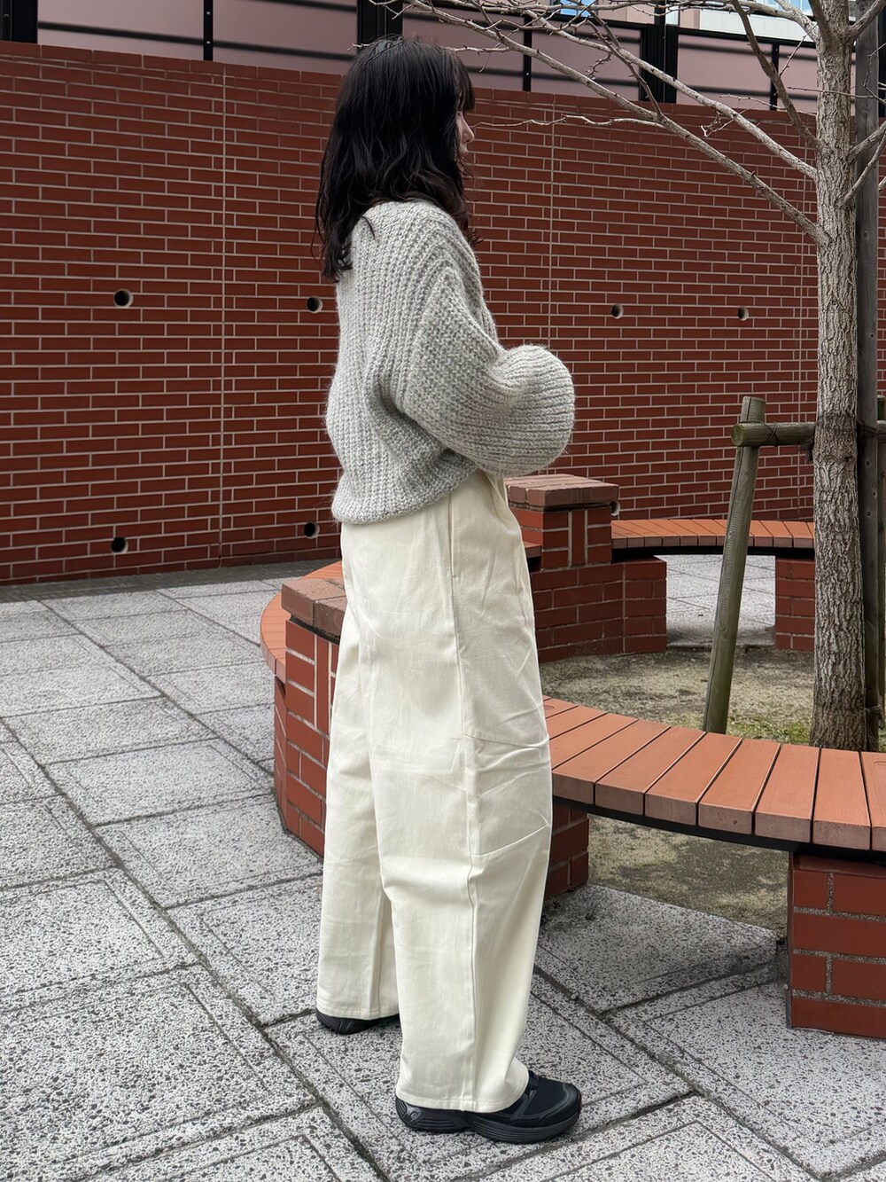 ホワイト系のチノパンツ、グレー系のニット/セーター、ブラック系のベルトを着用したレディースの冬コーディネートの2枚目の写真