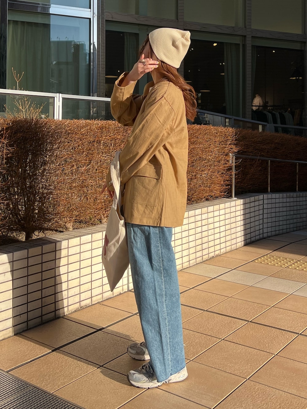 ブルー系のデニムパンツ、レッド系のトートバッグ、ベージュ系のテーラードジャケットを着用したレディースの春コーディネートの4枚目の写真