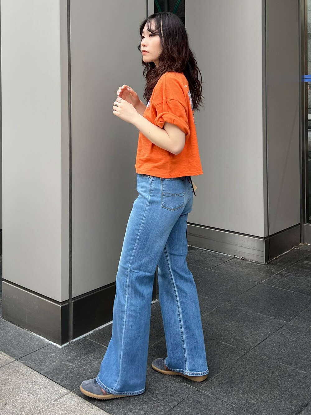 ブルー系のデニムパンツ、オレンジ系のTシャツ/カットソーを着用したレディースの春コーディネートの2枚目の写真