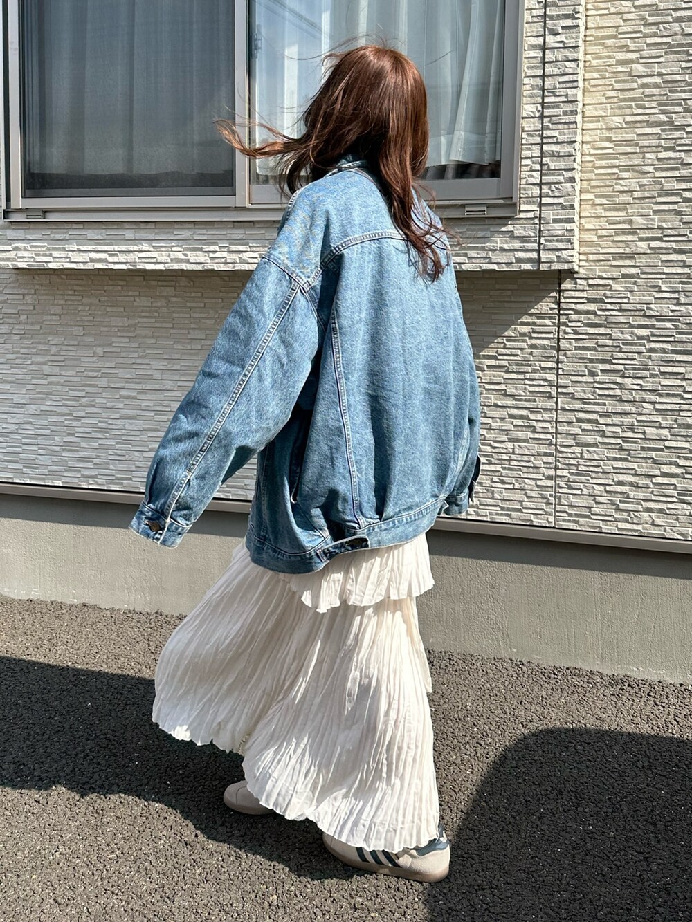 ブルー系のデニムジャケット、グレー系のスウェット、ホワイト系のスカートを着用したレディースの春コーディネートの3枚目の写真