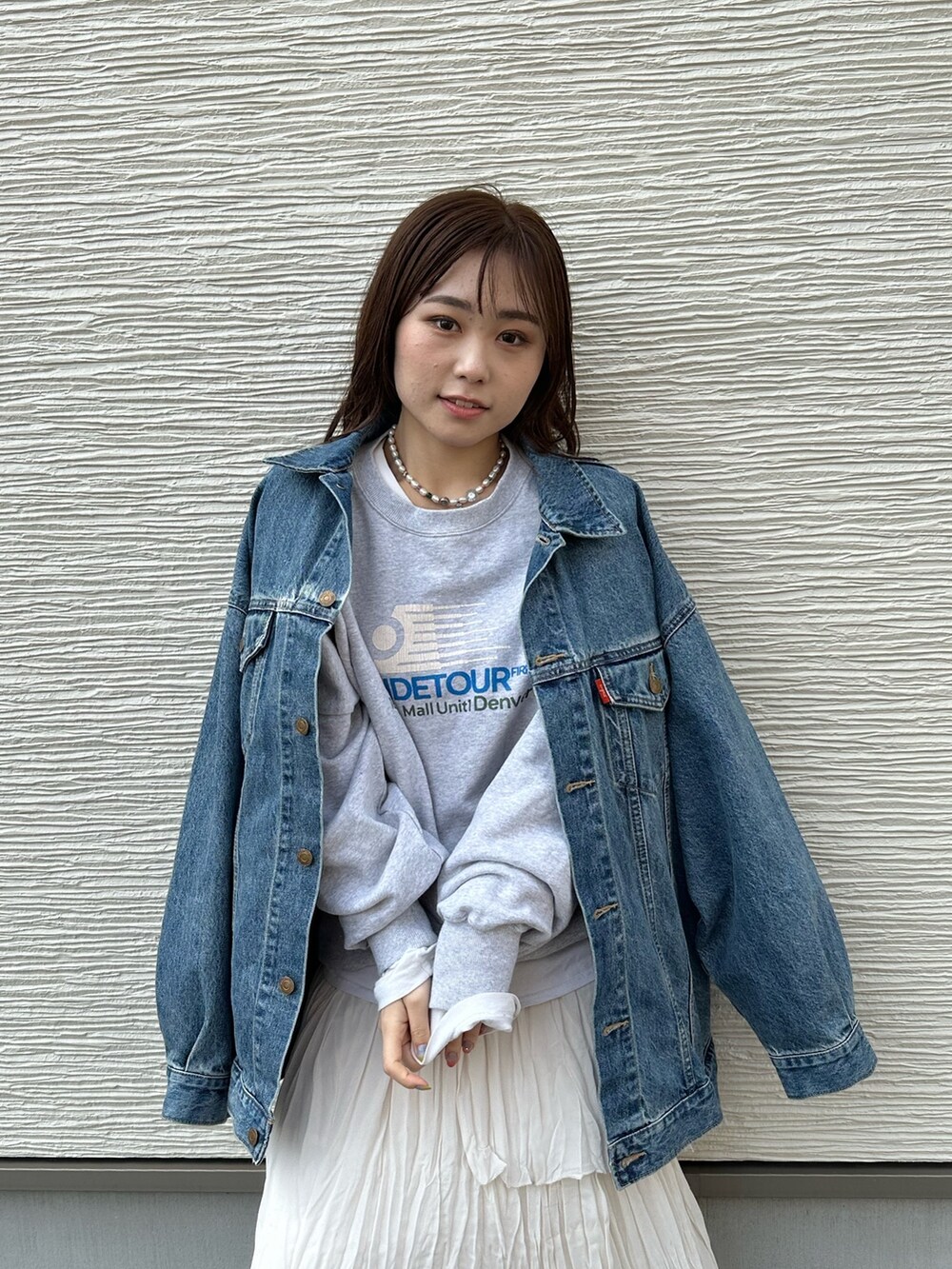 ブルー系のデニムジャケット、グレー系のスウェット、ホワイト系のスカートを着用したレディースの春コーディネートの6枚目の写真