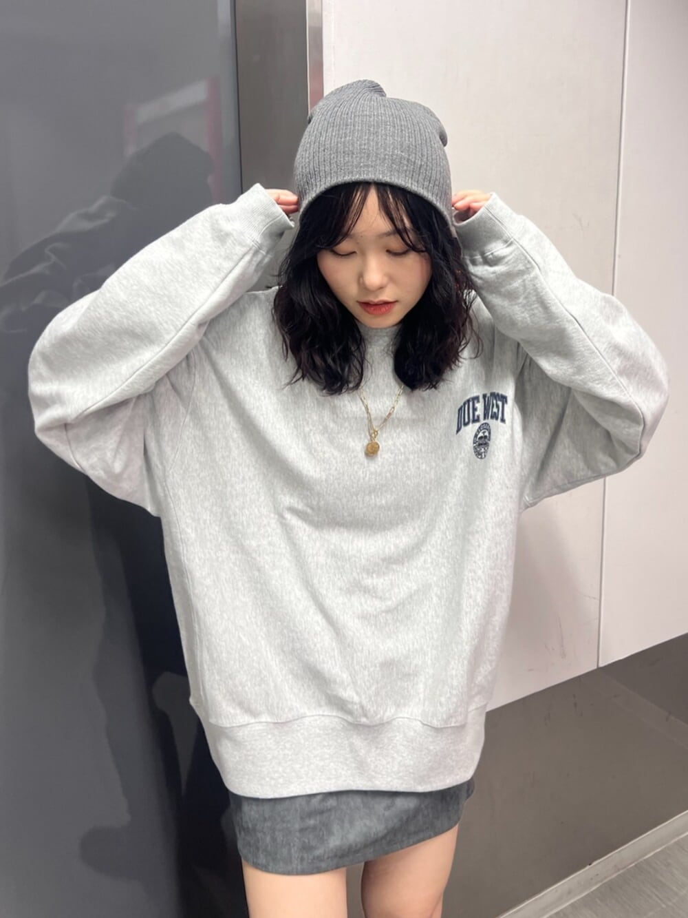 グレー系のスウェット、グレー系のスカート、ブラウン系のブーツを着用したレディースの秋コーディネートの4枚目の写真