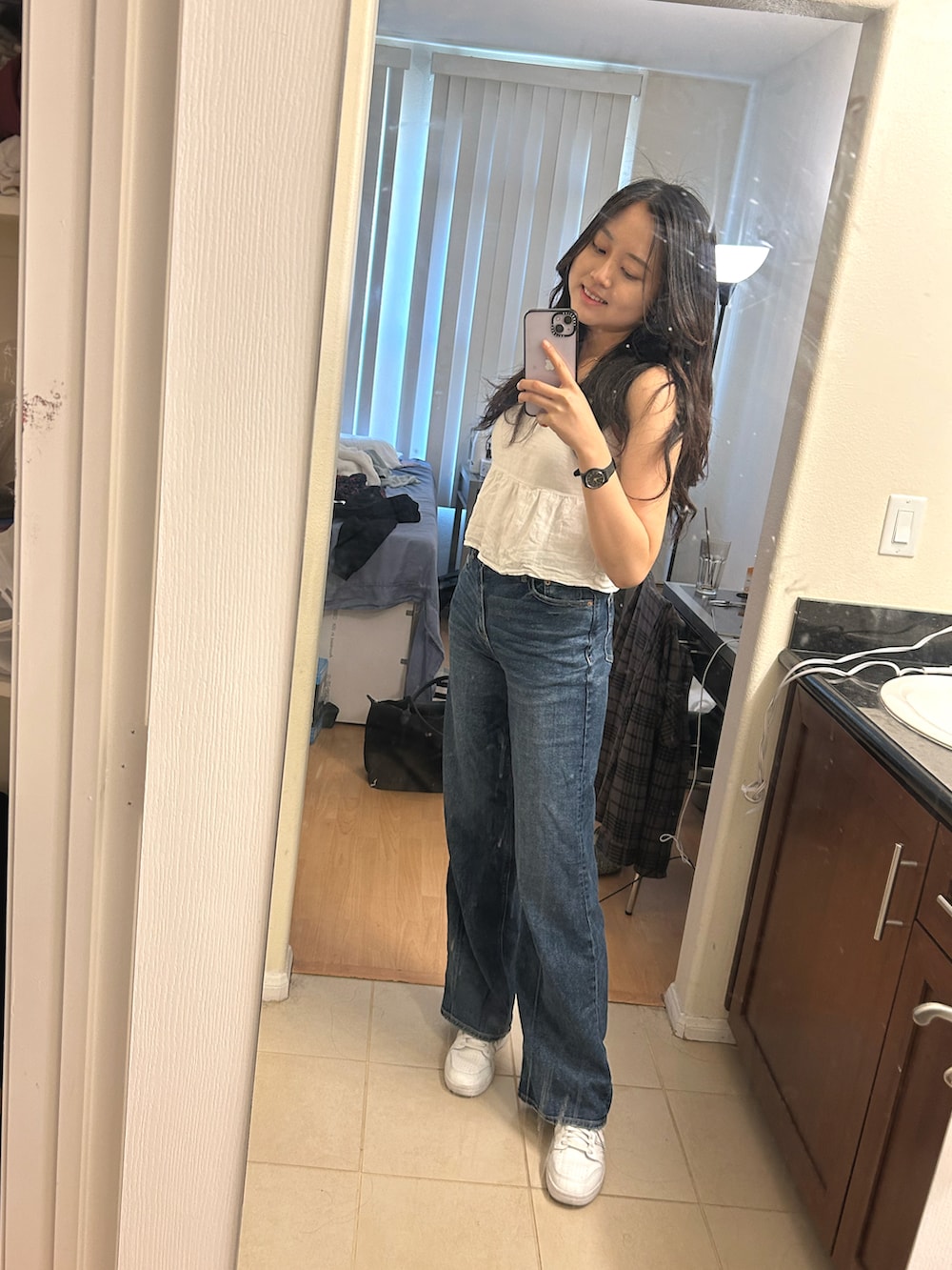 ブルー系のデニムパンツ、ホワイト系のスニーカー、ホワイト系のタンクトップを着用したレディースの春コーディネートの4枚目の写真