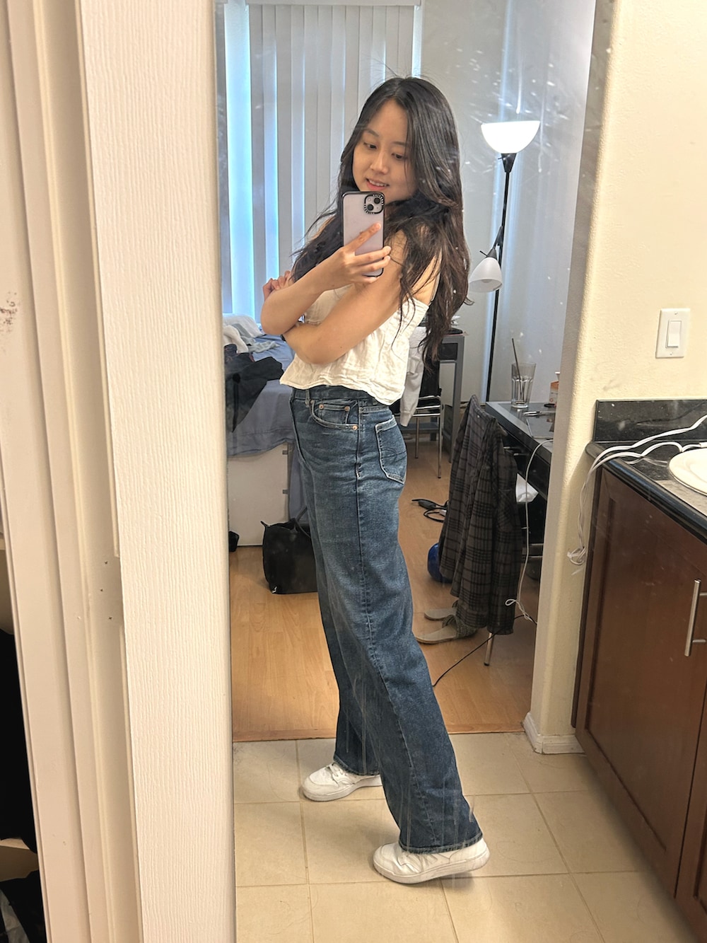 ブルー系のデニムパンツ、ホワイト系のスニーカー、ホワイト系のタンクトップを着用したレディースの春コーディネートの2枚目の写真