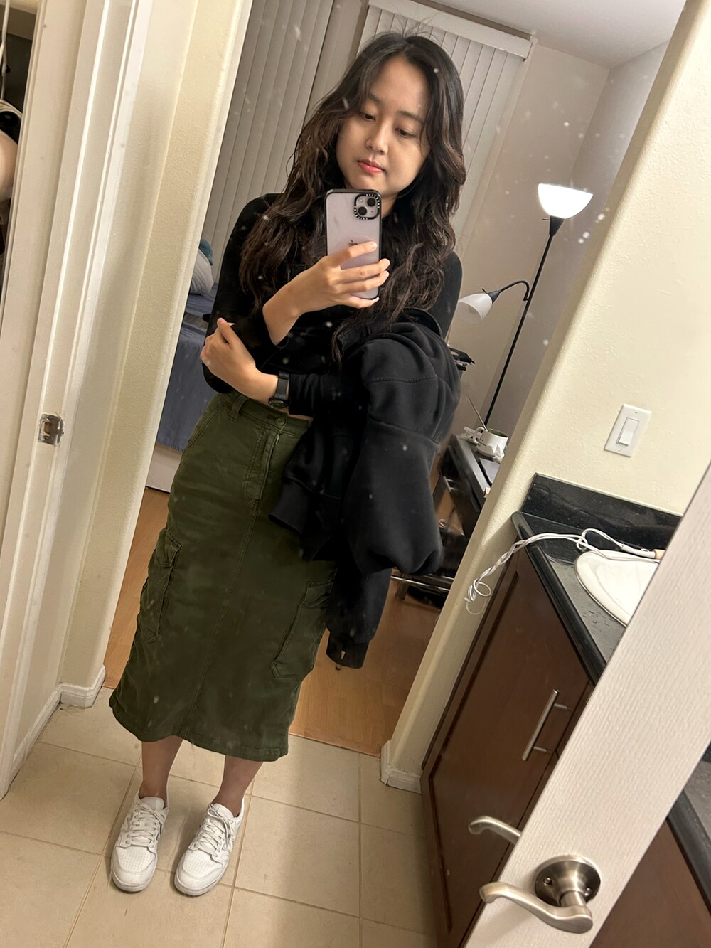 ブラック系のパーカー、ホワイト系のスニーカー、グリーン系のスカートを着用したレディースの秋コーディネートの2枚目の写真