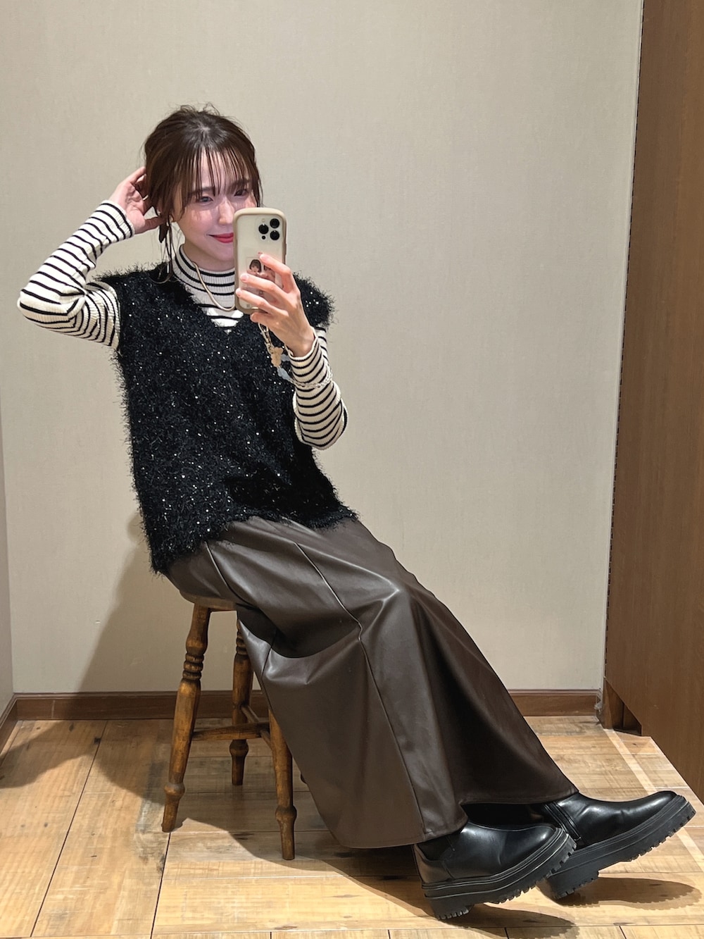 ブラック系のベスト、ブラウン系のスカート、ブラック系のブーツを着用したレディースの冬コーディネートの2枚目の写真