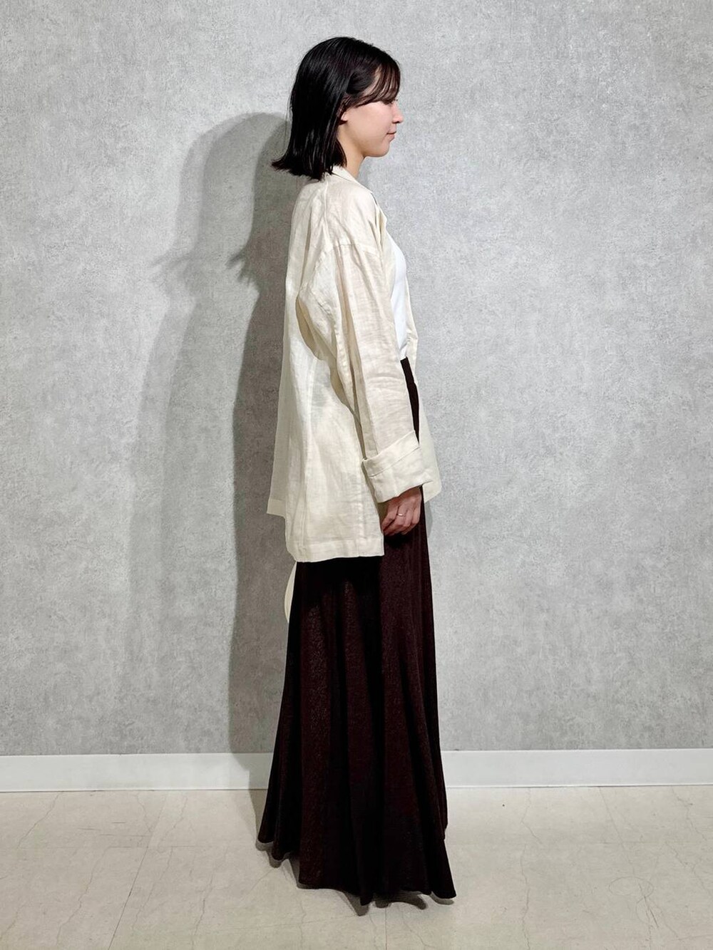 ホワイト系のハンドバッグ、ブラック系のパンプス、ブラウン系のスカートを着用したレディースの春コーディネートの4枚目の写真