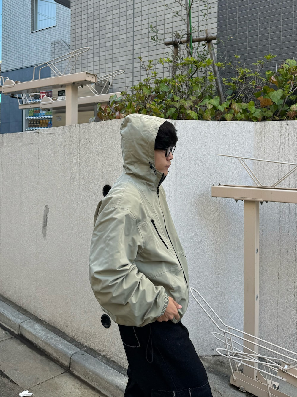 グリーン系のマウンテンパーカー、グレー系のデニムパンツ、ブラウン系のスニーカーを着用したメンズの秋コーディネートの2枚目の写真