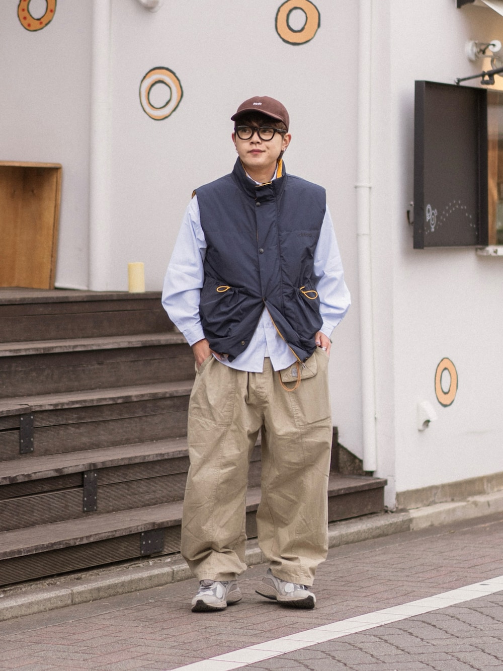 ブルー系のダウンベスト、グレー系のスニーカー、ブラウン系のキャップを着用したメンズの冬コーディネートの5枚目の写真